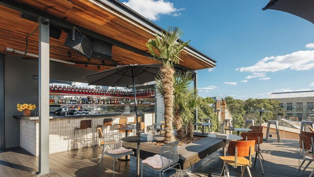 An outdoor bar area with wooden flooring, seating, and a bar stocked with bottles. - BRYK Hotel (Odesa)