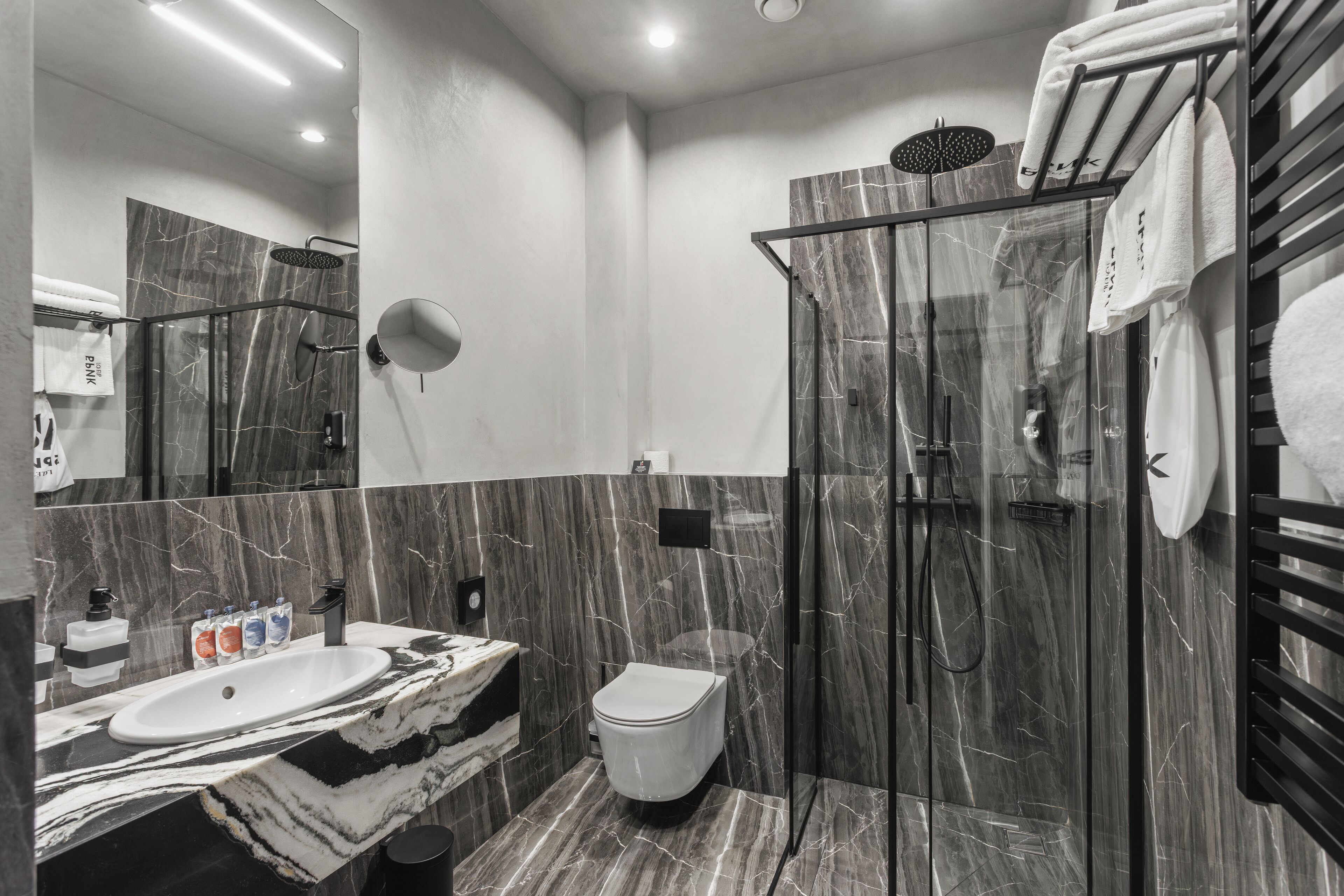 A modern bathroom with a marble vanity, a toilet, and a glass-enclosed shower.