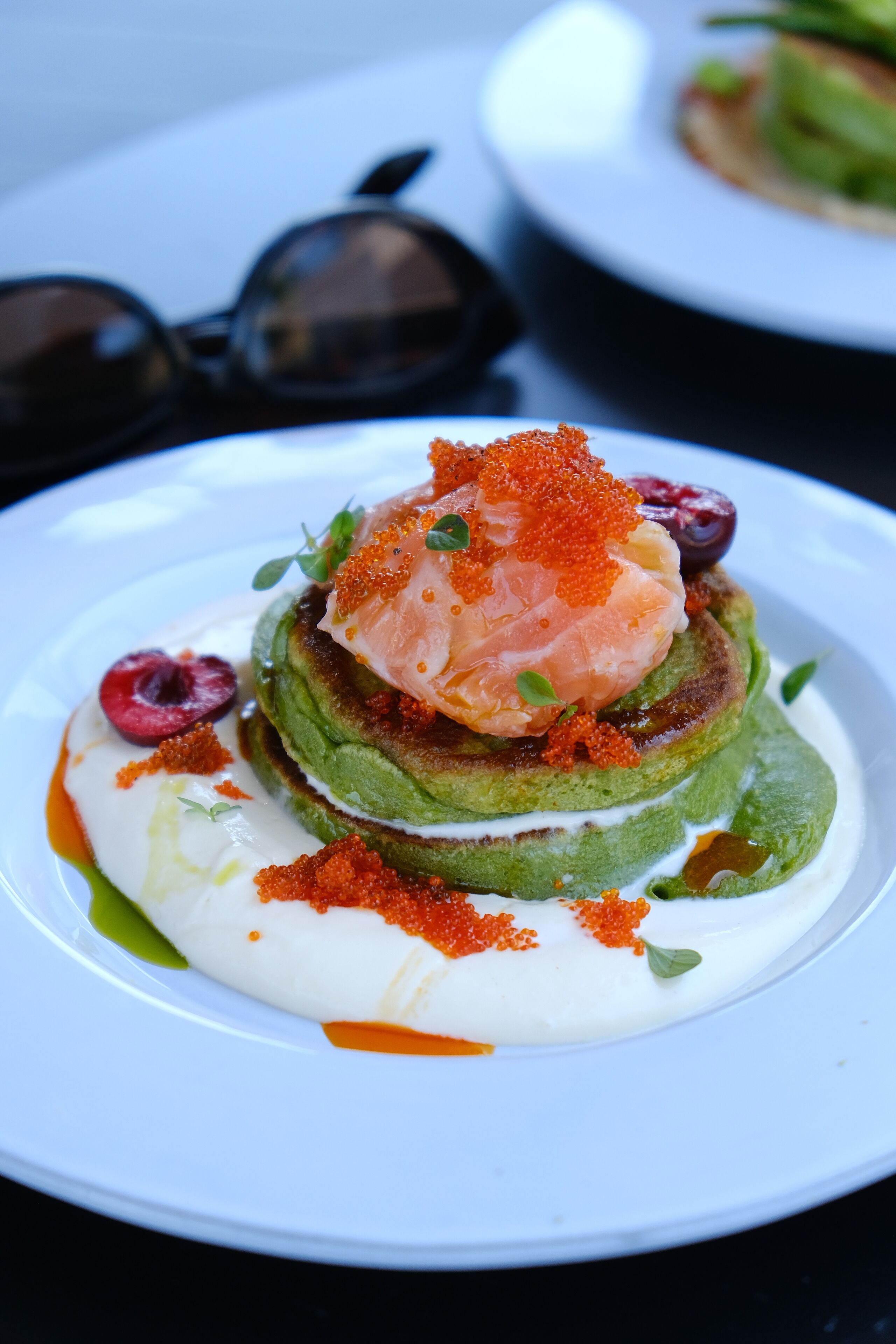 Ein Teller mit Essen, dazu Lachs, grüne Blätter und ein Klecks Sahne.