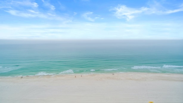 Ein Strand mit blauem Himmel und ruhiger See.