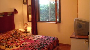 A bedroom with a bed, a television on a small table, a window with curtains, and a wall-mounted air conditioner. - Typical dwelling with garden & sea view on the Bay  (Scalea)