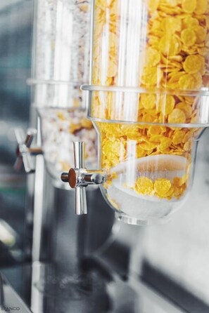 A cereal dispensing machine with multiple compartments filled with yellow cereal flakes. - Bianco Resort - Adults Only (Parga)