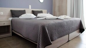 A neatly made bed with a grey quilt, two bedside tables with lamps, and a wardrobe in a modern hotel room. - Bianco Resort - Adults Only (Parga)