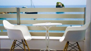 A balcony with two white chairs and a small round table, overlooking a calm sea with boats and a distant green hill. - Bianco Resort - Adults Only (Parga)
