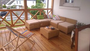 En træterrasse med fletmøbler, herunder en sofasæt og en stol.