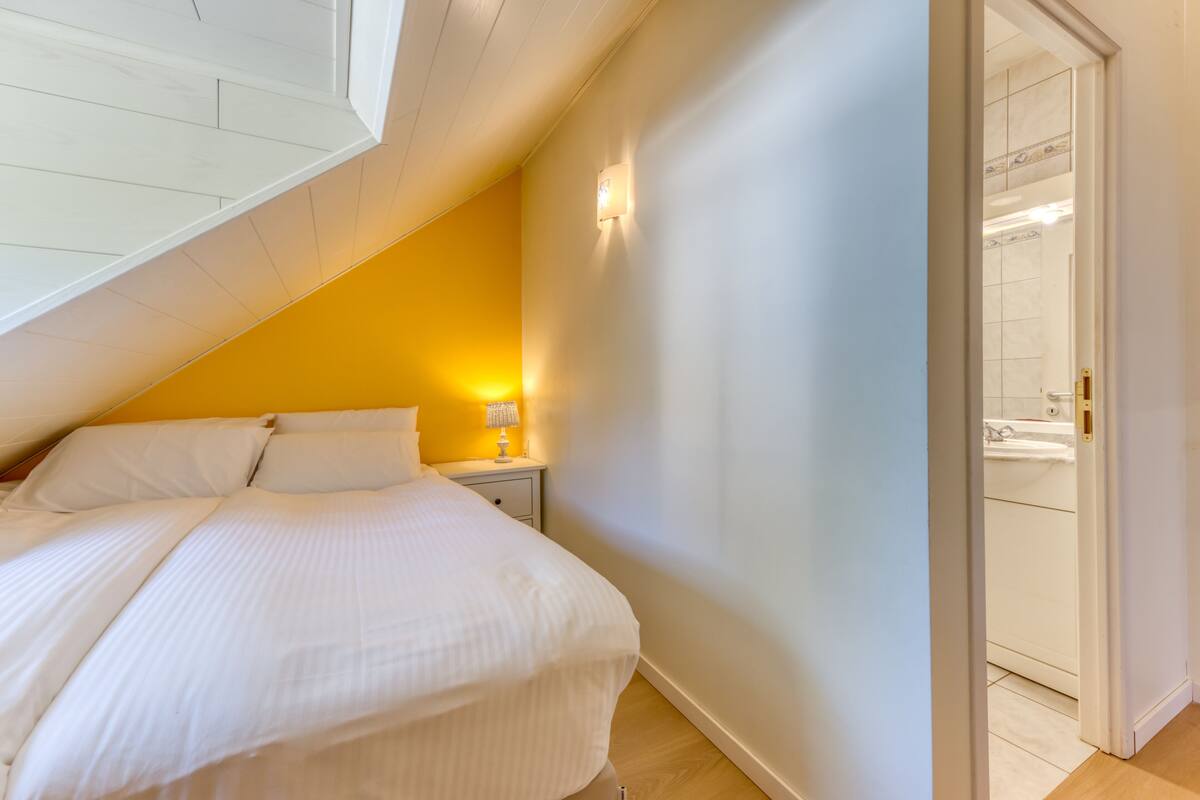 A bedroom with a bed, nightstand, and a wall-mounted light fixture.