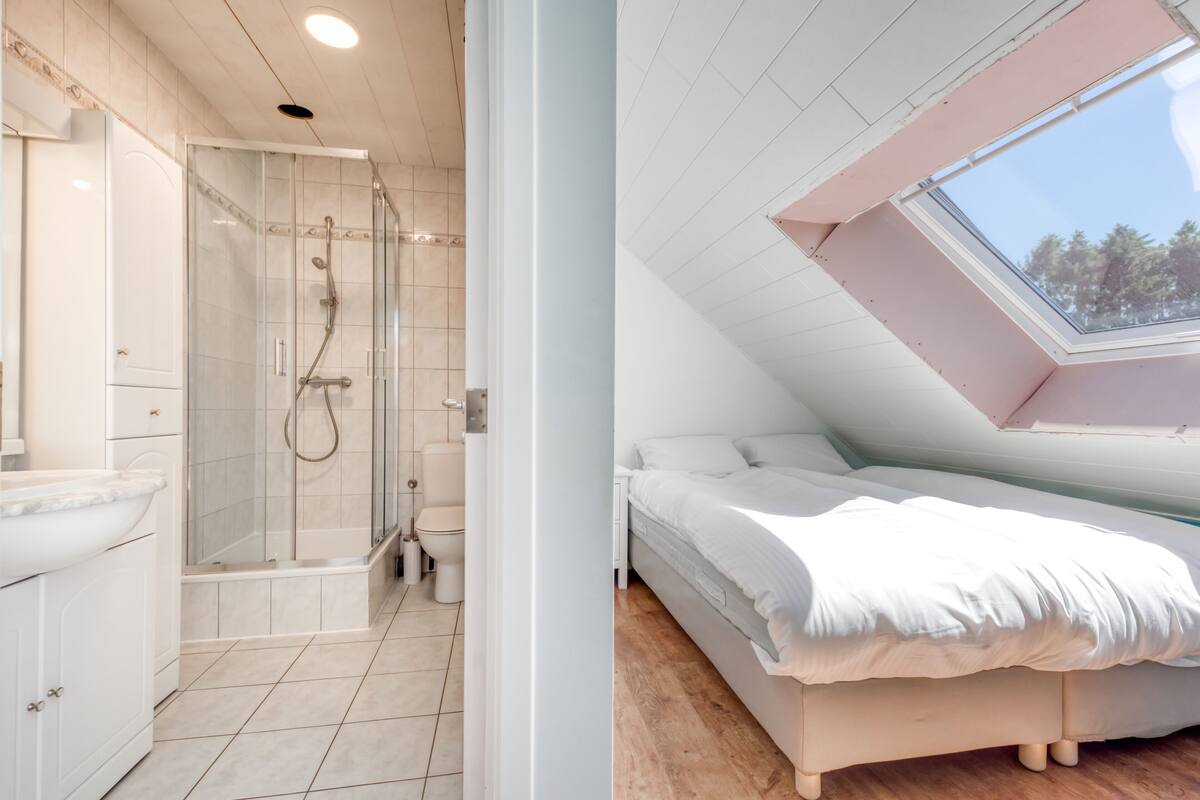 A modern bathroom with a glass-enclosed shower and a separate toilet.