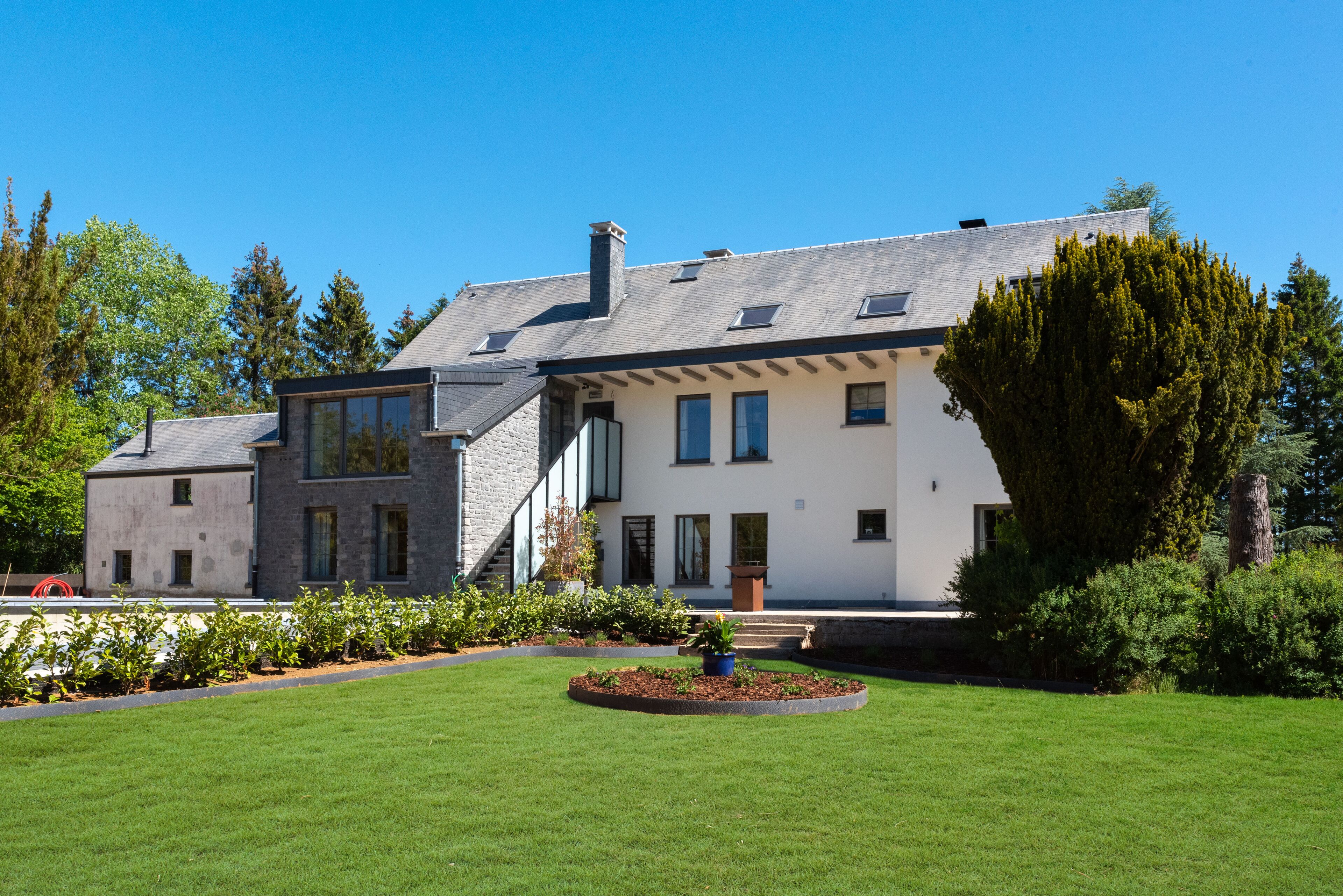 Una moderna casa a due piani con un prato e un giardino curati.