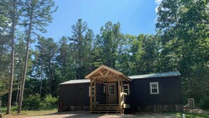 A small wooden cabin with a porch, surrounded by trees. - Secluded Ranch House Cabin in Eminence - Ozarks @ Old Desperado Ranch (Eminence)