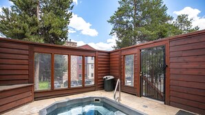 A wooden deck with a hot tub, stone flooring, and large windows. - Pine Ridge Incline Condo: Ski-In, Walk To Downtown (Breckenridge)