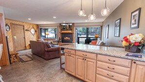 A spacious kitchen with a large island, wooden cabinets, and a stone backsplash. - Pine Ridge Incline Condo: Ski-In, Walk To Downtown (Breckenridge)