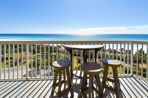Ein Balkon mit Meerblick, zwei hölzerne Hocker und ein Tisch.