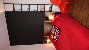Ett modernt rum med en färgskala i svart och vitt, en röd soffa med en prydnadskudde med Union Jack-mönster och en avskärmning av träribbor.