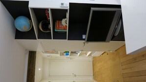 Ett litet rum med en inbyggd säng, en liten hylla med en jordglob och böcker samt en väggpanel av trä.