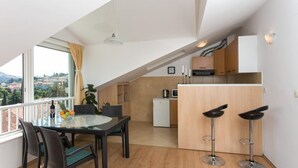 A modern kitchen with a dining area, a small refrigerator, and a view of the city. - Apartment Lala (Dubrovnik)