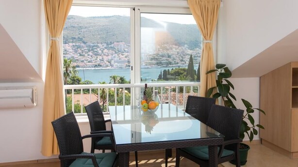 A balcony with a glass table, four chairs, and a potted plant. - Apartment Lala (Dubrovnik)