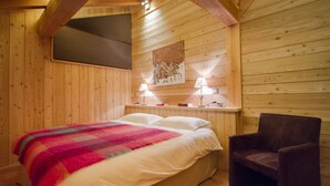 Camera da letto in una baita di legno, con un letto, una sedia e un comodino con lampade.