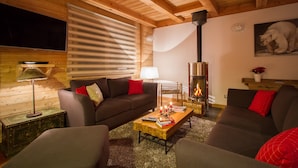 Un accogliente soggiorno con camino, soffitto in legno e un divano.
