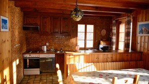 A rustic kitchen with wooden cabinets, a stove, and a sink. - Chalet Le Roitelet (Evolène)