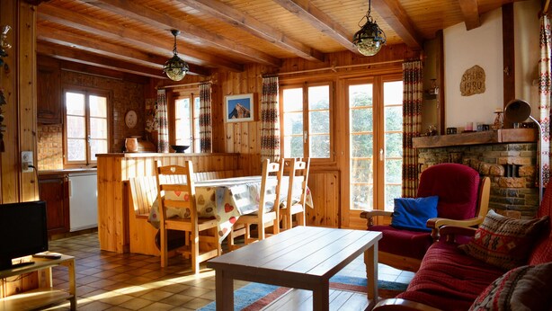 A wooden interior with a dining table, chairs, a sofa, and a fireplace. - Chalet Le Roitelet (Evolène)