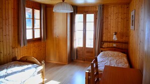 A wooden cabin room with a bed, a desk, and a window. - Chalet Le Roitelet (Evolène)