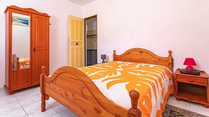 Un dormitorio con cama de madera, un armario, una mesita de noche y un espejo.