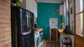 Une cuisine de taille réduite équipée d’un lave-linge, d’un réfrigérateur et d’un évier.