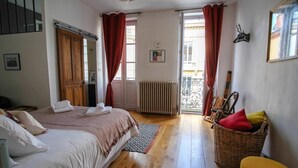 Une chambre avec deux lits, un panier en osier, un tabouret jaune et un radiateur.