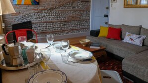 Un coin repas avec une table dressée pour quatre personnes, une cafetière et divers verres.