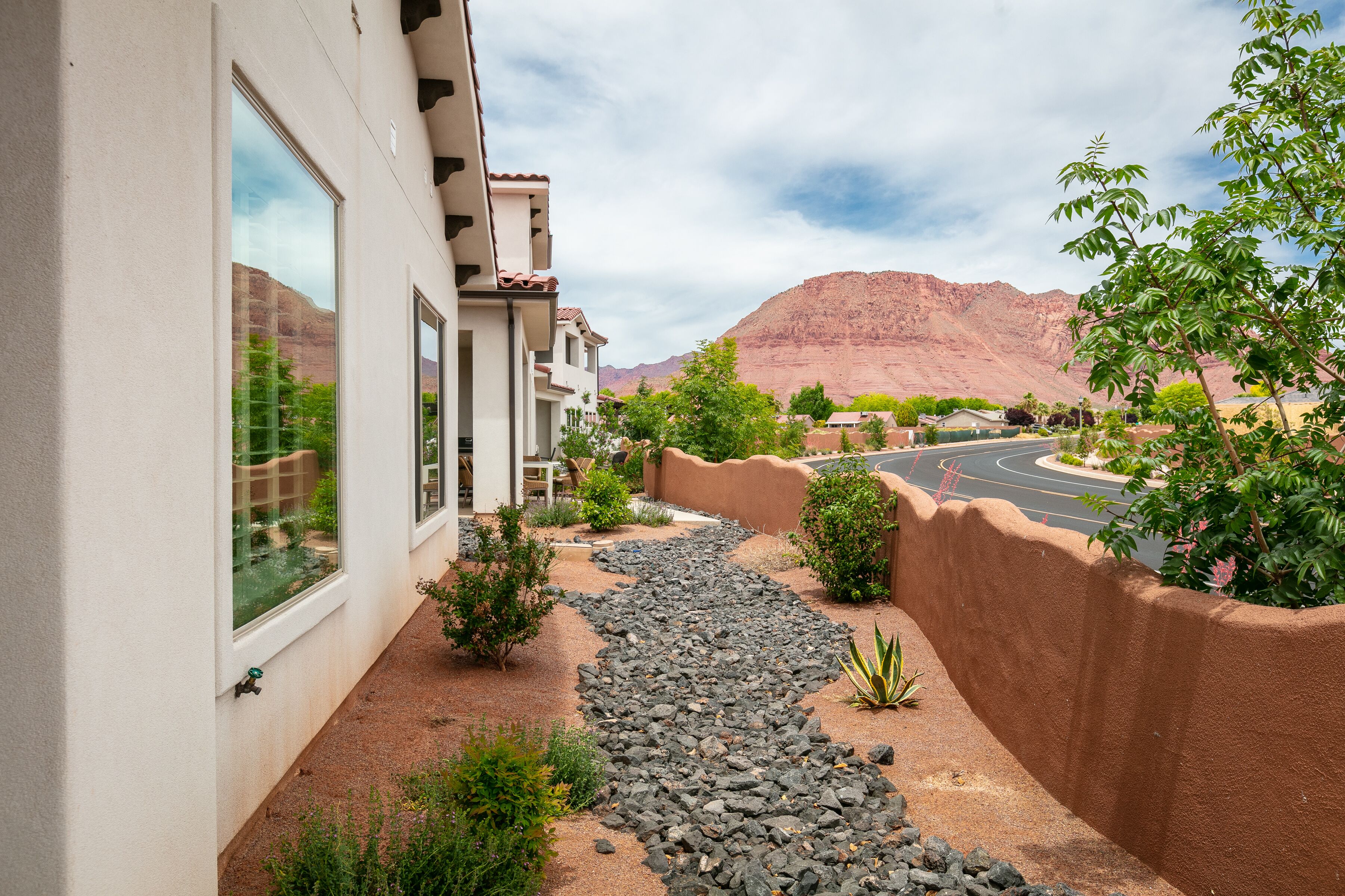 Zona residencial con camino de entrada pavimentado, sendero de piedra y vista a una cadena montañosa.