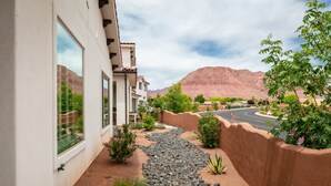 Zona residencial con camino de entrada pavimentado, sendero de piedra y vista a una cadena montañosa.