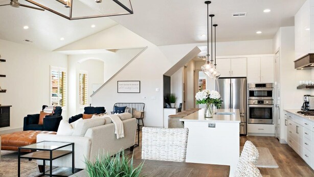 Una cocina moderna con electrodomésticos de acero inoxidable, una isla central y un comedor con mesa y sillas de madera.