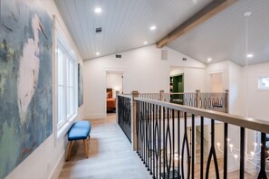 Stylish hallway with a high ceiling, wooden beam structure, and a large abstract painting.