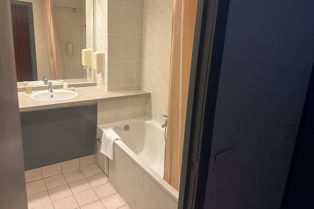 A bathroom with two sinks, a mirror, a bathtub, and a shower curtain.