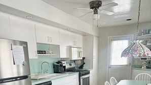Et moderne køkken med rustfrie apparater, et spiseområde med bord og stole samt en loftsvifte.