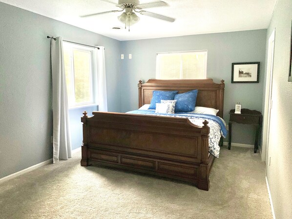 A bedroom with a wooden bed, a ceiling fan, a window with blinds, and a framed picture on the wall. - Devil's Lake Cottage - Family Friendly a block from State Park Entrance! Skiing (Baraboo)