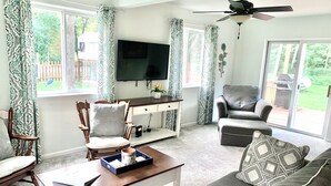 Una sala de estar con sofá, sillón, mesa de centro, televisor y escritorio.