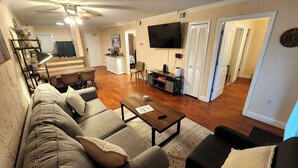 A living room with a sofa, coffee table, and TV. There is a staircase leading to another room. - Newly Renovated Hilton Head Resort Beach Condo - 2 Bedroom - Private Balcony (Hilton Head Island)
