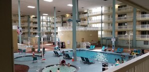 Una piscina interior con varios niveles de balcones, sillones de descanso y una zona de piscina central.