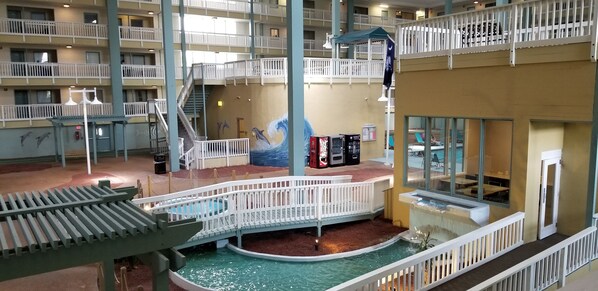 Un atrium intérieur à plusieurs niveaux, doté d’un élément aquatique central, de rampes et d’une fresque représentant des dauphins.