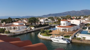 Une ville côtière aux bâtiments blancs, dotée d’un port de plaisance et bordée par une chaîne de montagnes.