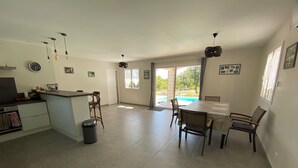 A spacious kitchen with a dining area, a bar, and a view of a swimming pool. - Villa 135m2 private swimming pool (open from May to September) (Labeaume)