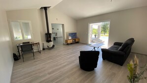 A spacious living area with a fireplace, a sofa, a TV, and a dining area visible through a glass door. - Villa 135m2 private swimming pool (open from May to September) (Labeaume)