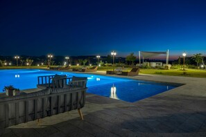 Relax by the pool surrounded by a paved deck and lounge chairs.