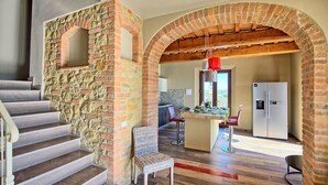 Ein modernes Interieur mit Steinwand, einer Holztreppe und einer Küchenzeile inklusive Kühlschrank.