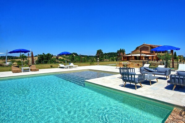 Relax by the pool surrounded by comfortable seating and umbrellas for shade.