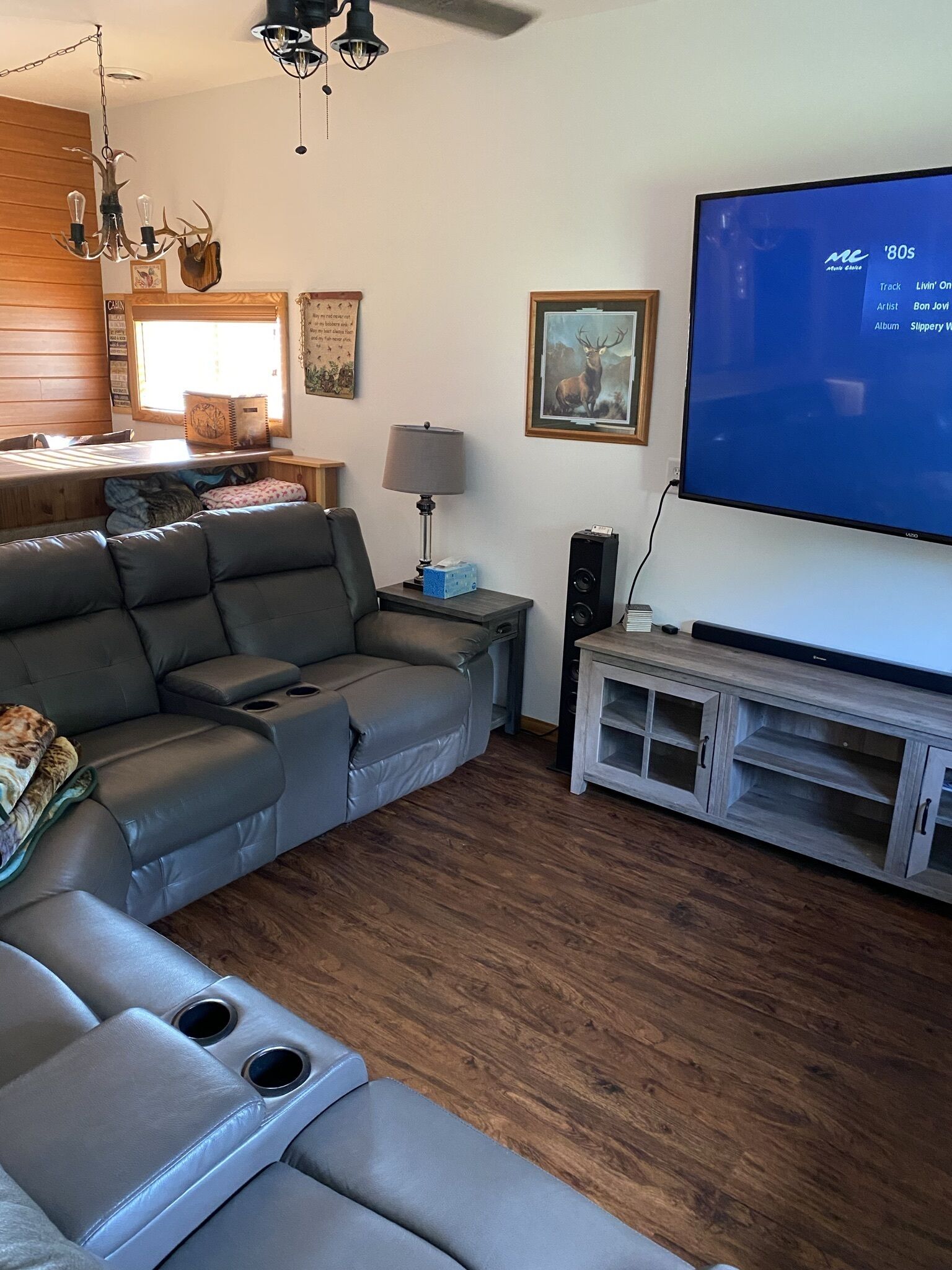 A modern living room with a sectional sofa, a flat-screen TV, and a wooden floor.