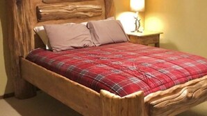 A bed with a wooden headboard and a red plaid bedspread. - Piece of Paradise / Private Hot Tub (Holcombe)