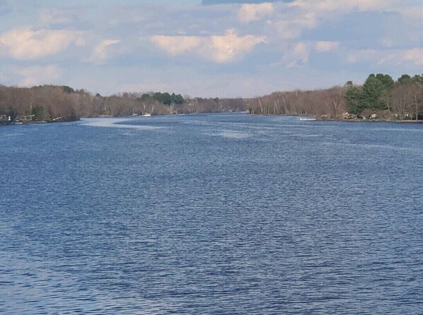 A wide view of a calm lake with a forested shoreline and a few boats.