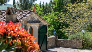 Un edificio in pietra con tetto a tegole, una porta verde e una piccola finestra.